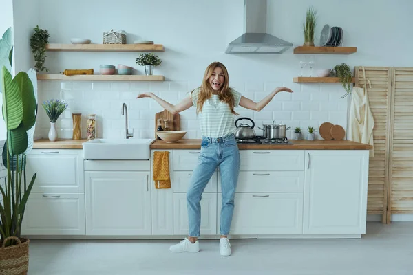Genç ve güzel bir kadın. Mutfakta mutlu görünüyor.