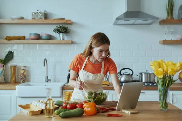 Koncentrerad Ung Kvinna Matlagning Och Använda Digitala Tablett När Står — Stockfoto