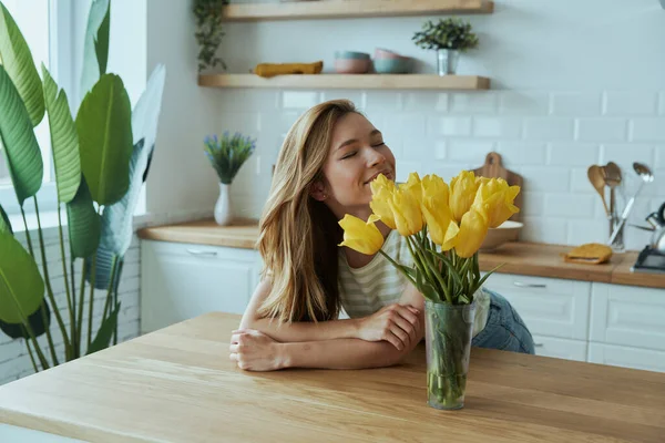 Szczęśliwa Młoda Kobieta Pochyla Się Kuchni Pachnie Żółtymi Tulipanami — Zdjęcie stockowe