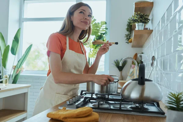 Hermosa Mujer Joven Degustación Sopa Mientras Cocina Cocina Doméstica — Foto de Stock