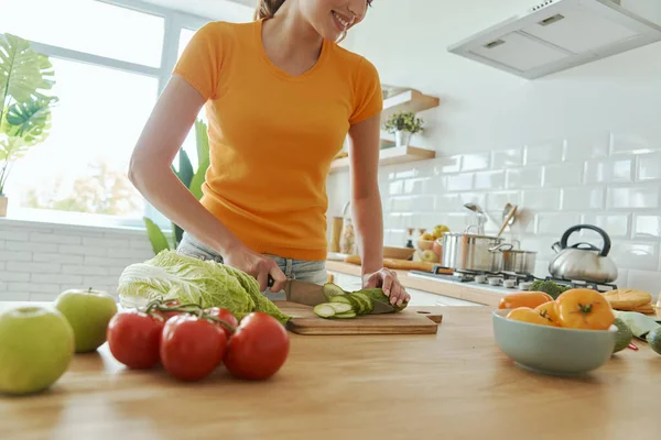 Ev mutfağında sebze doğrayan genç bir kadının yakın çekimi.