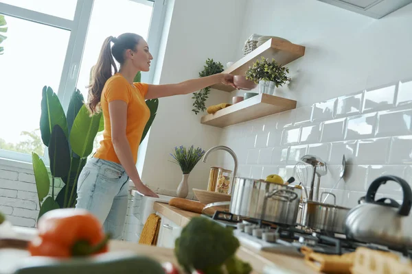 Mujer Joven Confiada Poniendo Platos Estante Mientras Está Pie Cocina — Foto de Stock