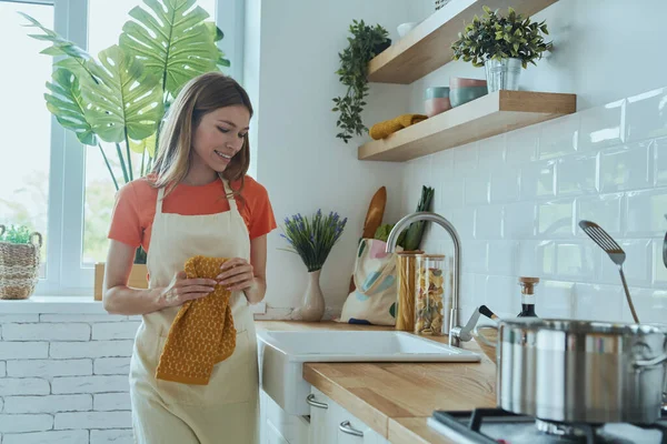 Genç ve güzel bir kadın evcil mutfakta bulaşıkları yıkıyor.