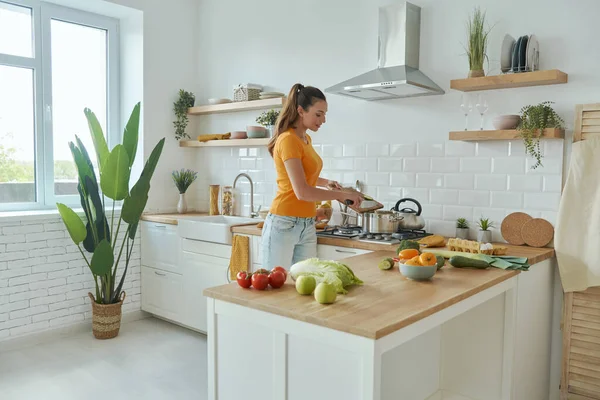 Modern mutfakta yemek pişiren kendinden emin genç bir kadın.