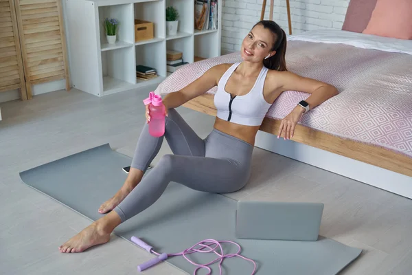 Spor elbiseli güzel bir kadının evde antrenman yaptıktan sonra dinlenmesi.