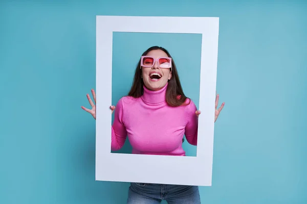 Opgewonden Jonge Vrouw Kijken Door Een Fotolijstje Terwijl Staan Tegen — Stockfoto