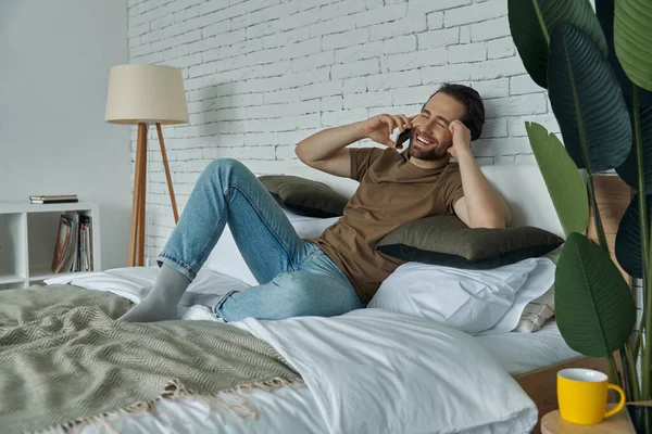 Glada Ung Man Som Använder Mobiltelefon Medan Kopplar Hemma — Stockfoto