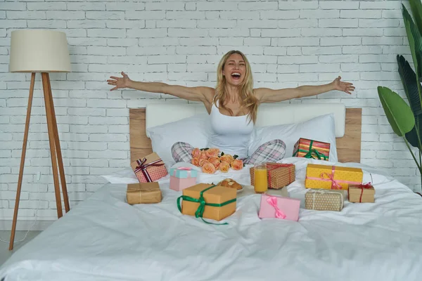 Красива Жінка Виглядає Щасливою Сидячи Ліжку Подарунковими Коробками Лежать Поруч — стокове фото