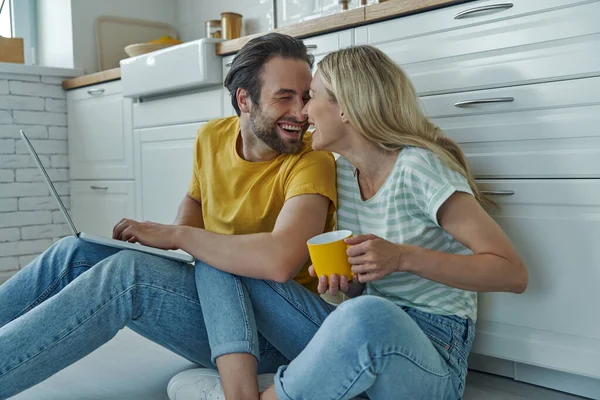 Happy Couple Using Laptop While Sitting Floor Leaning Kitchen Counter — Stock Photo, Image
