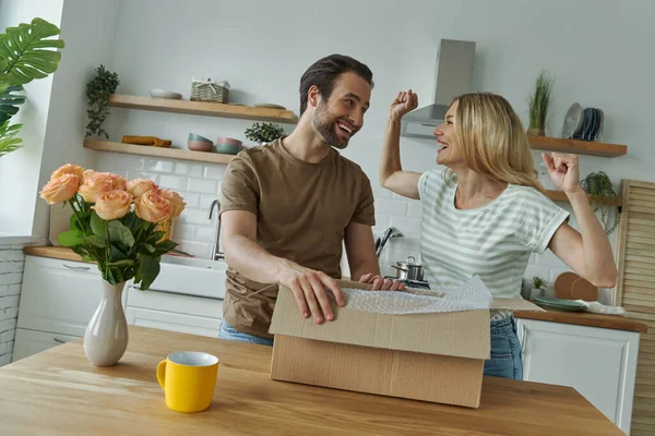 Heyecanlı genç çift kutuları açıyor ve evdeki mutfakta dururken gülümsüyor.