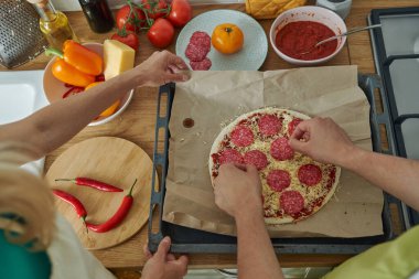 Salamlı ev yapımı pizza yapan iki kişinin en iyi görüntüsü.