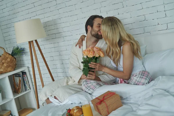 Egy Fiatalember Megcsókolja Barátnőjét Virágot Neki Miközben Mindketten Ágyban Ülnek — Stock Fotó