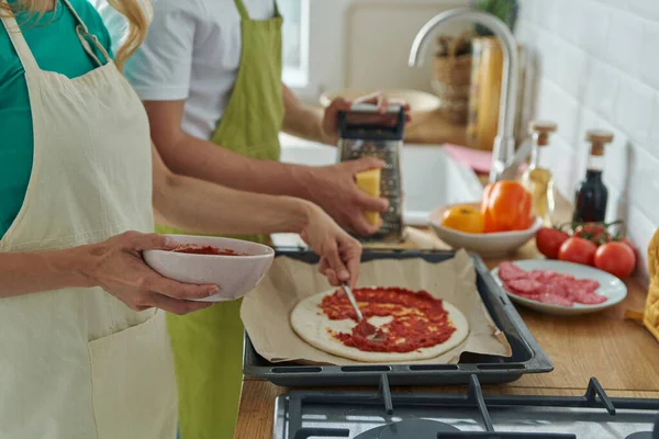キッチンに立っている間に自家製のピザを作るカップルのクローズアップ — ストック写真