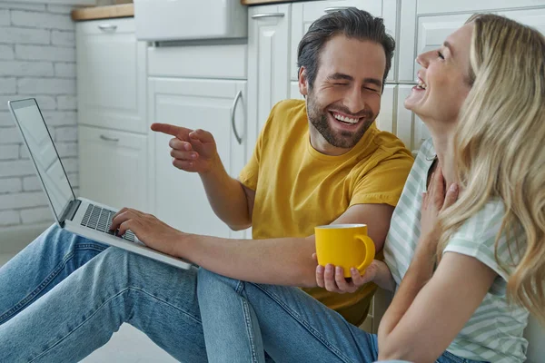 Feliz Jovem Casal Usando Laptop Enquanto Sentado Chão Inclinado Balcão — Fotografia de Stock