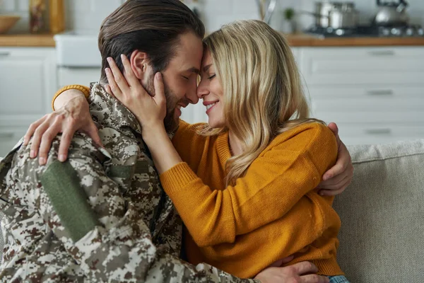 Cheerful man in military form hugging his wife after coming home from war