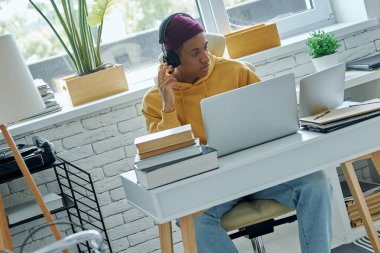 Ofiste çalışırken dizüstü bilgisayar kullanan kulaklıklı kendine güvenen bir ırkçı.