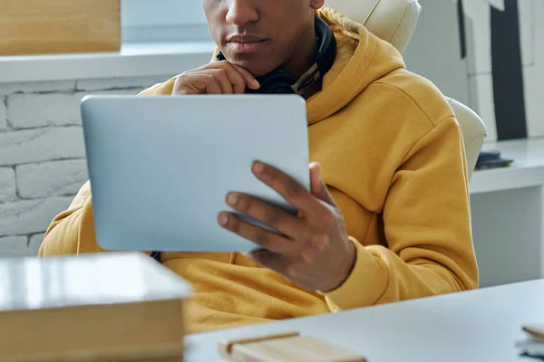 坐在工作位置时 坐在耳机里自信的混血男子使用数字平板电脑 — 图库照片