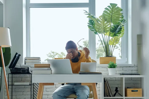 Ofisinde çalışırken burnuna masaj yapan yorgun genç bir adam.