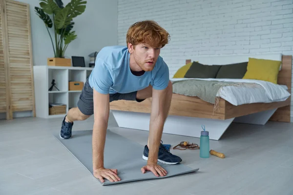 Handsome young man in sports clothing exercising at home