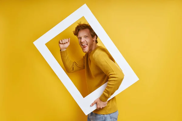 Happy Man Looking Picture Frame Gesturing While Standing Yellow Background — Stock Photo, Image