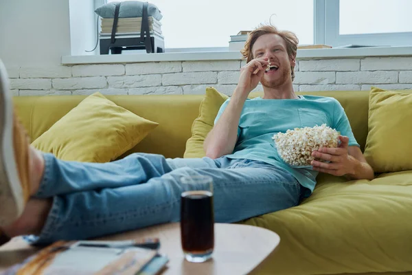 Fröhlicher Junger Mann Genießt Snacks Während Hause Auf Der Couch — Stockfoto