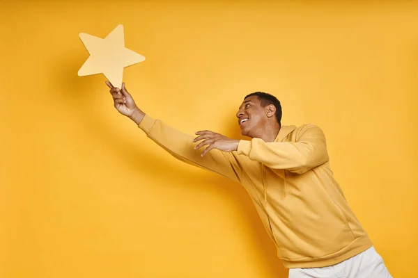 Juguetón Mixto Hombre Captura Estrella Amarilla Contra Fondo Amarillo —  Fotos de Stock