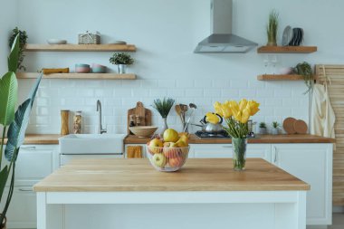 Mutfağın iç kısımları beyaz mobilyalar ve parlak elementlerle dolu.