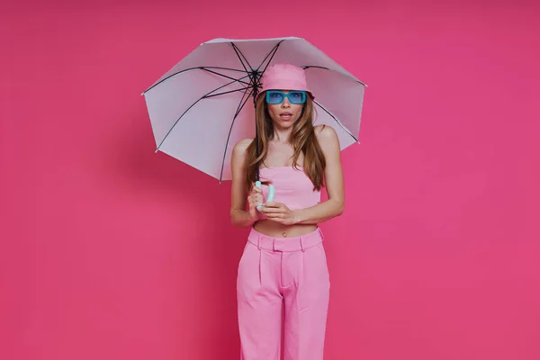 Ελκυστική Νεαρή Γυναίκα Μοντέρνα Ρούχα Κρατώντας Ομπρέλα Ενώ Στέκεται Ροζ — Φωτογραφία Αρχείου