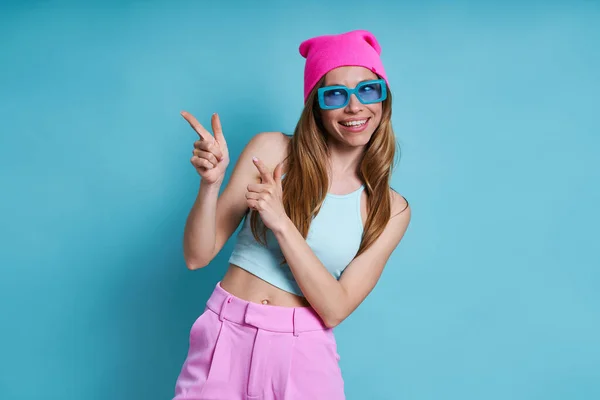 Atractiva Joven Mujer Sombrero Rosa Sonriendo Apuntando Hacia Otro Lado —  Fotos de Stock