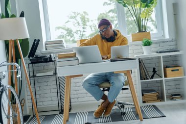 Ofiste çalışırken cep telefonuyla konuşan kendinden emin, melez bir genç.