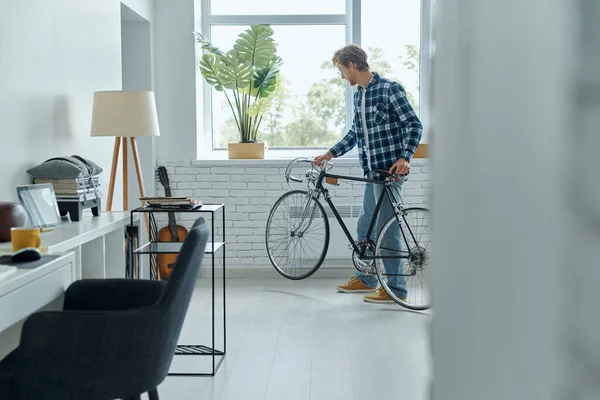 Unge Man Undersöker Sin Cykel När Han Står Vardagsrummet — Stockfoto