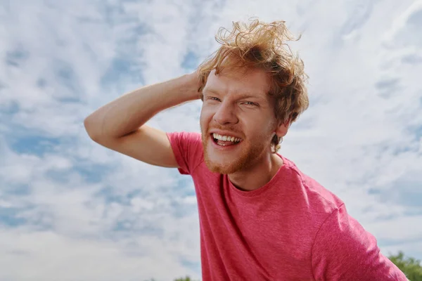 年轻英俊的红头发男子看着相机 背对着天空微笑 — 图库照片