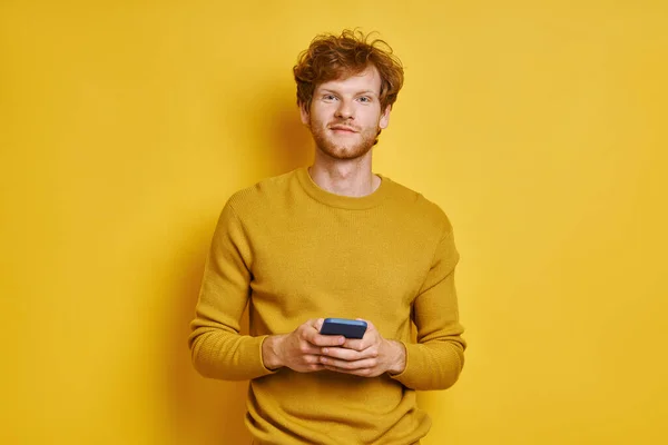 Bello Rossa Uomo Possesso Cellulare Mentre Piedi Contro Sfondo Giallo — Foto Stock