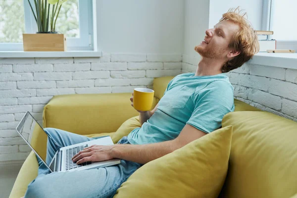 Relajado Pelirrojo Hombre Usando Ordenador Portátil Disfrutar Bebida Caliente Mientras — Foto de Stock