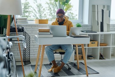 Ofiste çalışırken gülümseyen kendinden emin genç bir ırk adamı.
