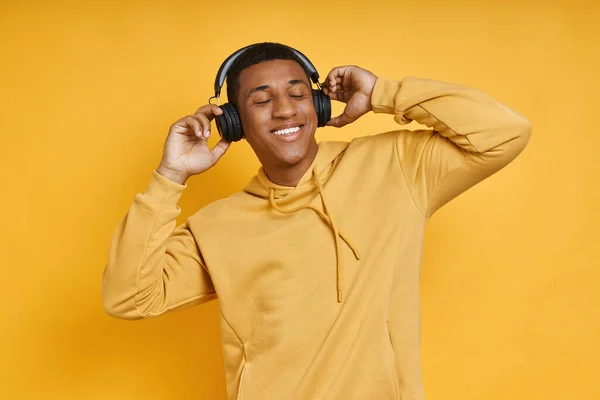 Wesoły Mieszany Człowiek Wyścig Słuchawkach Korzystających Muzyki Stojąc Żółtym Tle — Zdjęcie stockowe