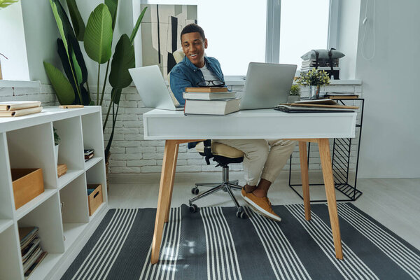 Cheerful young mixed race man smiling while sitting at his working place in office