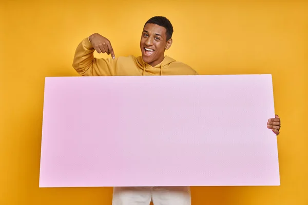 Счастливый Смешанный Расовый Человек Несущий Знамя Указывающий Стоя Желтом Фоне — стоковое фото
