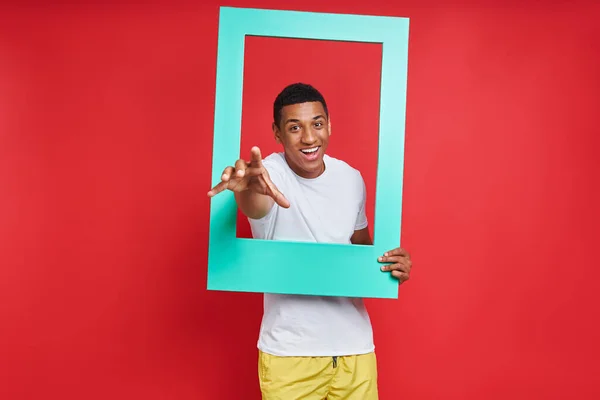 Playful Mixed Race Man Gesturing While Looking Picture Frame Red — Stock Photo, Image