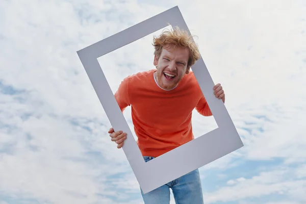 Playful Young Redhead Man Looking Picture Frame Smiling While Standing — Stock Photo, Image