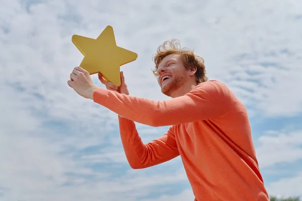 Ευτυχισμένος Νεαρός Κοκκινομάλλης Κρατώντας Κίτρινο Αστέρι Και Χαμογελώντας Τον Ουρανό — Φωτογραφία Αρχείου