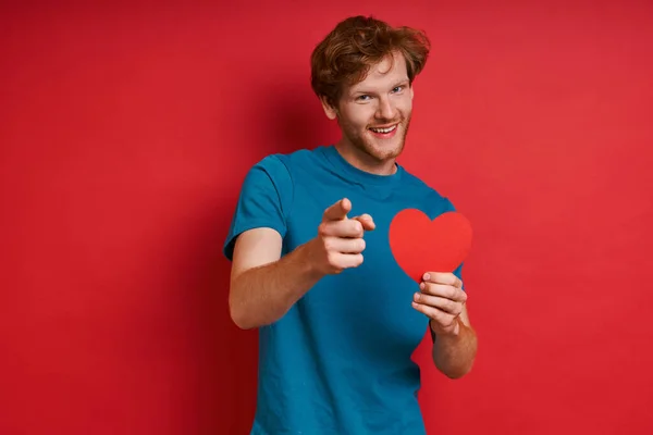 Cheerful Redhead Man Holding Red Paper Heart Pointing While Standing — Stock Photo, Image
