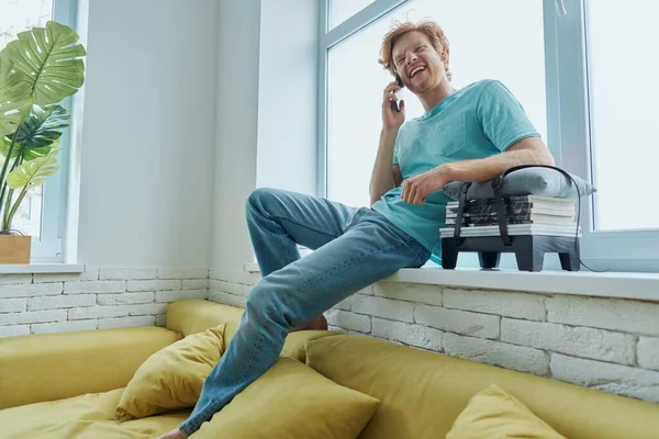 Handsome Redhead Man Talking Mobile Phone While Sitting Window Sill — Stockfoto