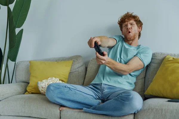 Homem Ruivo Brincalhão Usando Controlador Enquanto Joga Videogames Sofá Casa — Fotografia de Stock