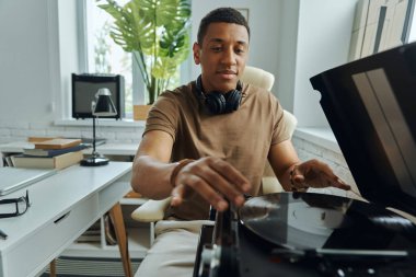 Neşeli genç Afrikalı turntable 'a plak koyuyor.