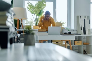 Ofiste çalışırken bilgisayarla konuşan mutlu bir Afrikalı.