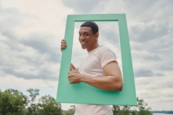 Hombre Africano Feliz Mirando Través Marco Imagen Gestos Mientras Está —  Fotos de Stock