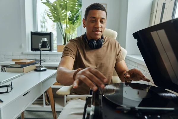 Neşeli genç Afrikalı turntable 'a plak koyuyor.