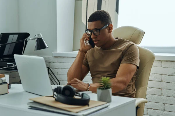 Elfoglalt Fiatal Afrikai Férfi Beszél Mobiltelefonon Miközben Dolgozik Irodában — Stock Fotó
