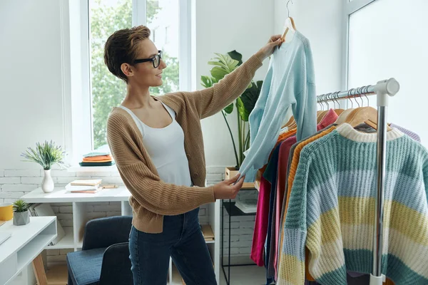 Confiant Jeune Femme Examinant Les Vêtements Tout Travaillant Dans Bureau — Photo